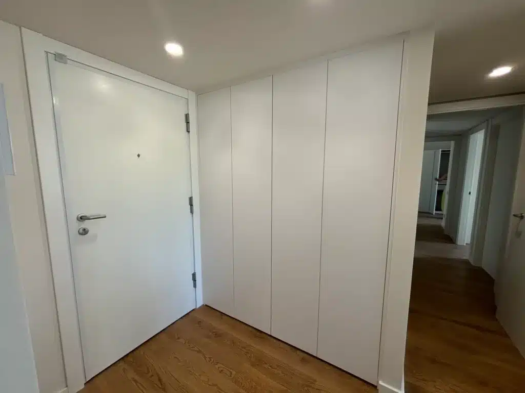 Armario de recibidor a medida blanco enrasado junto a la puerta de entrada