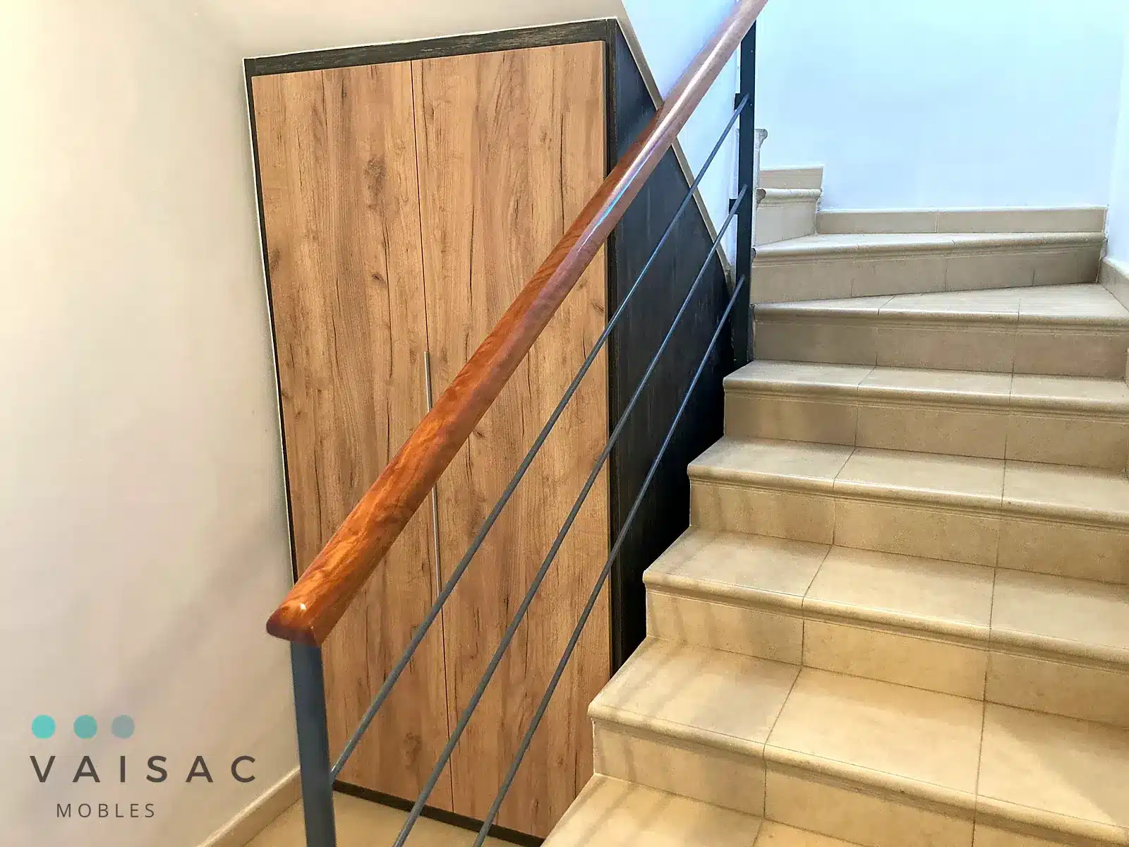 Armario a medida bajo escalera con puertas en roble y perfil negro junto a barandilla de madera