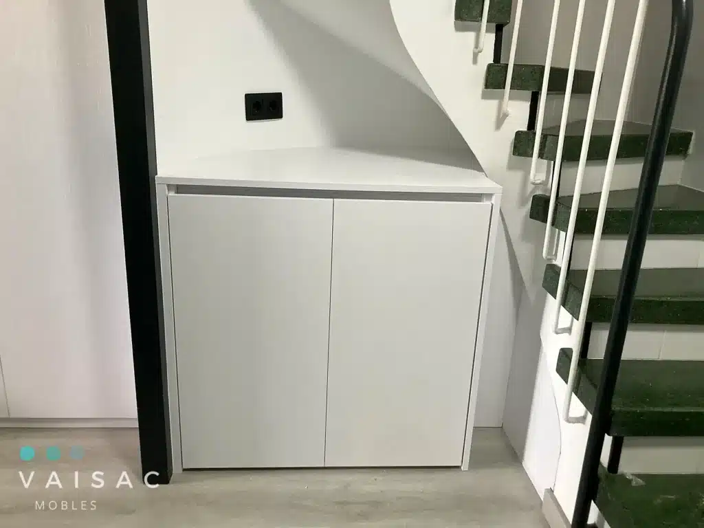 Mueble bajo blanco con puertas lisas a medida encajado bajo una escalera con encimera